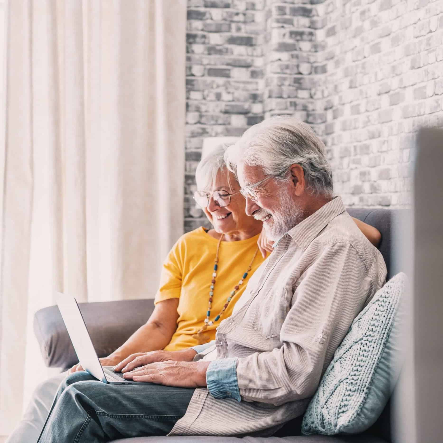 Elderly couple smiling at a laptop